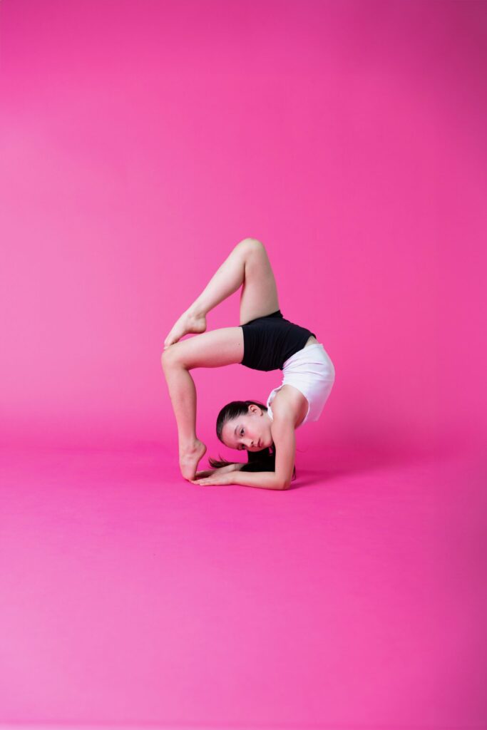 Evelyne doing a back bend, with Pink Background
